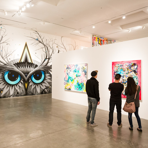 three people viewing artwork on a wall
