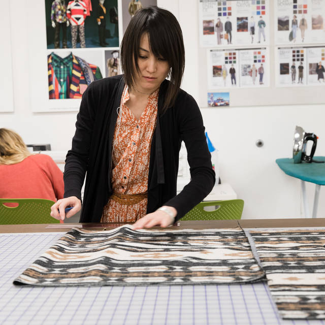 A student lays out her fabric on a cutting table