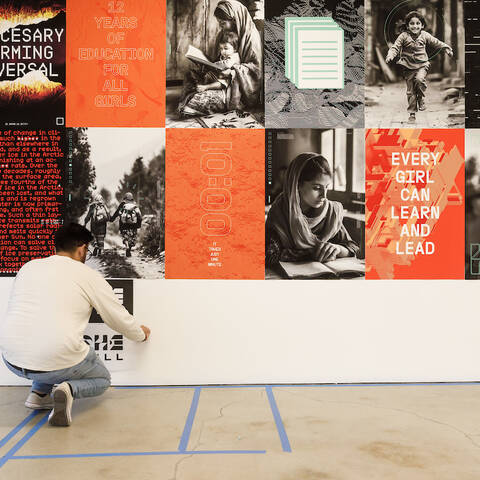 Graphic Design student hangs their work on the wall for critique
